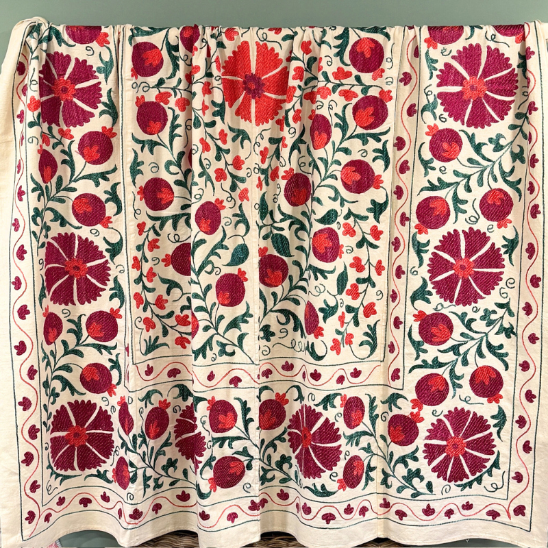 A unique, one-off hand embroidered Suzani textile in greens, plum and orange/red.