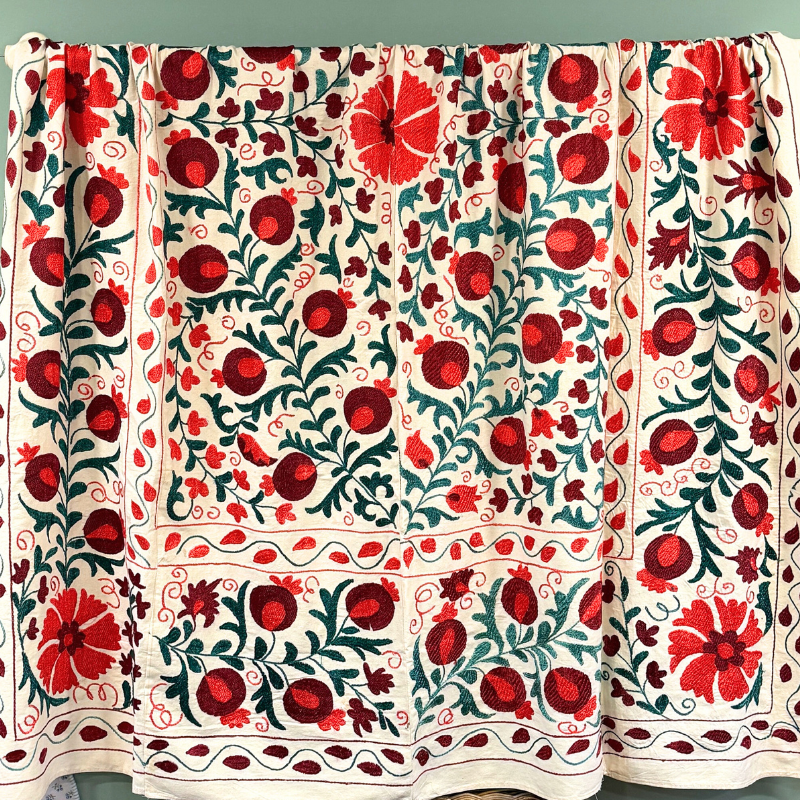 A unique, one-off hand embroidered Suzani textile in a beautiful colour palette of greens, plum and orange/red.