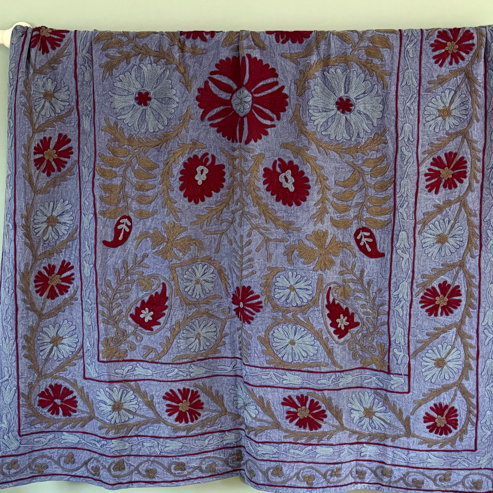 A unique, one-off hand embroidered floral cotton Suzani textile in a beautiful colour palette on blue mottled ground.