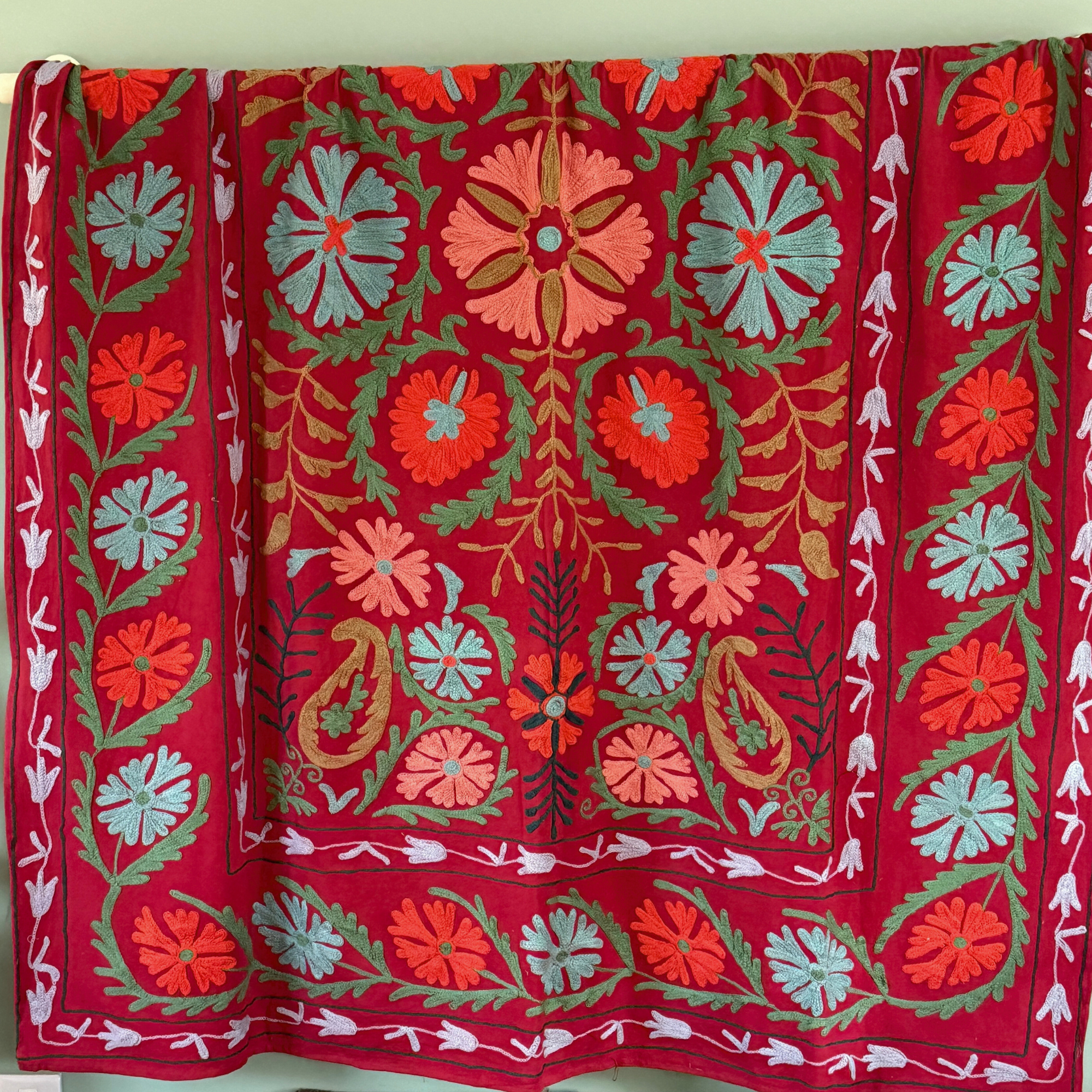 A unique, one-off hand embroidered floral cotton Suzani textile in red, blue, orange and green.