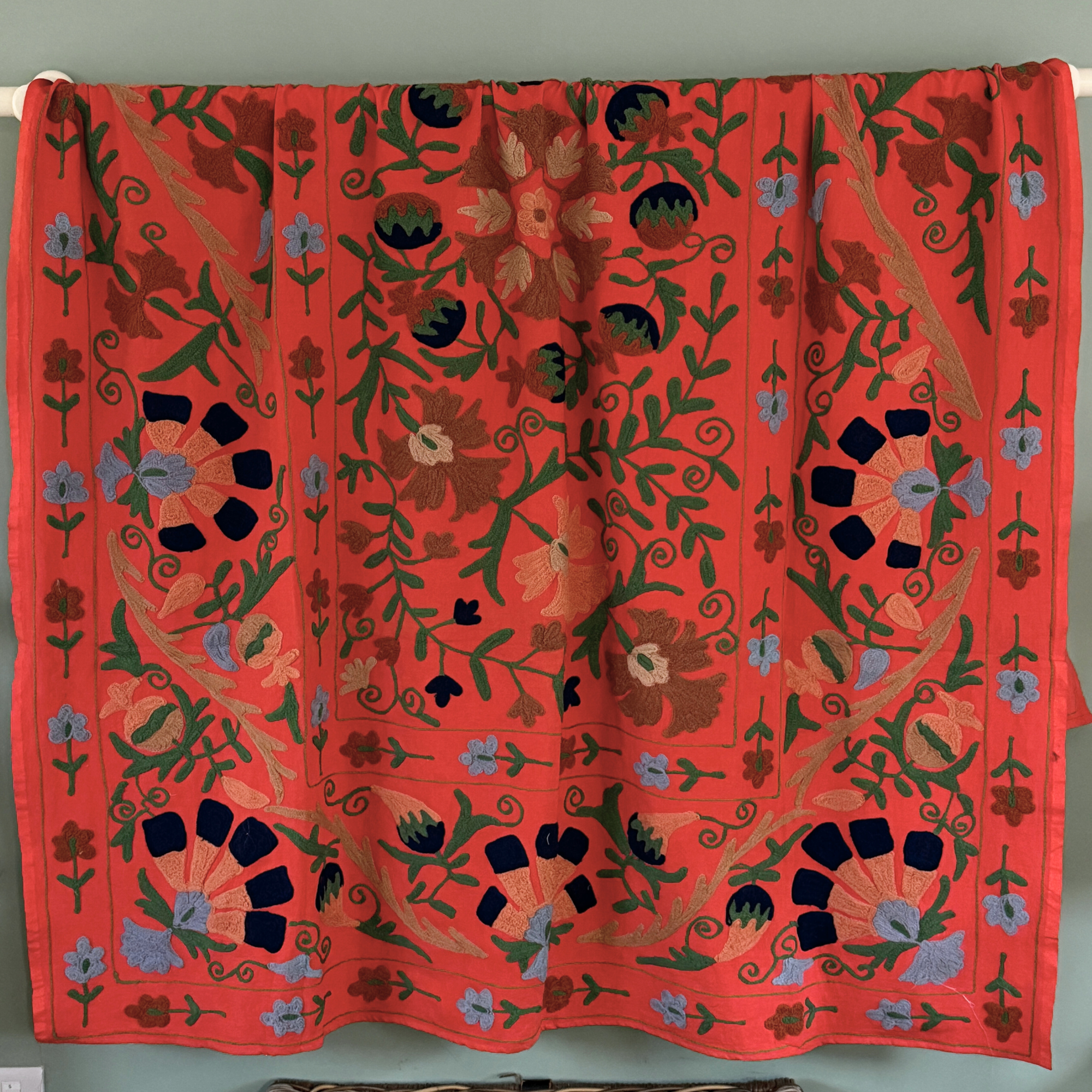 A unique, one-off hand embroidered cotton Suzani textile in a beautiful colour palette on terracotta/orange ground.