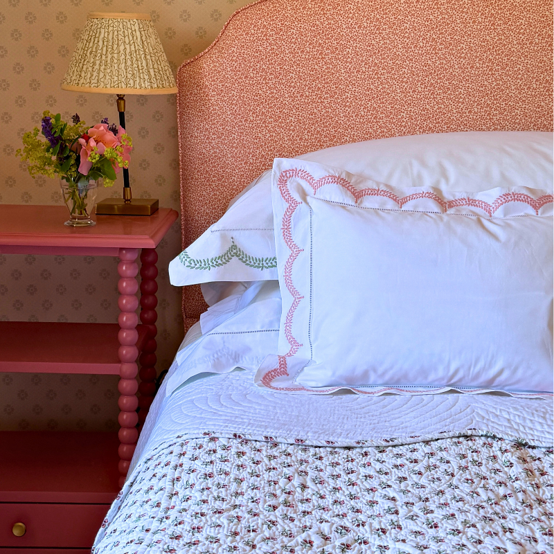 A white cotton scalloped edge bedspread with pink floral reverse